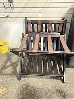 Front view of stacked folding luggage racks showing wood frame and straps