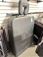 Front view of folded black massage bed with attached face cradle