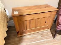 Full view of closed pine chest showing honey finish, paneled front, base molding