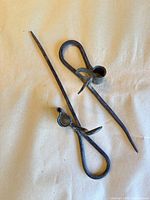 Both forged iron sticking candle holders laid flat showing full forms