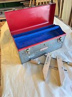 Open gray Craftsman toolbox with red interior and blue tray, two wooden Jorgensen clamps visible