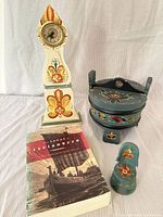 Group shot showing all four items: clock, tine box, book, small figure