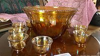 wide view of amber carnival glass punch bowl with eight cups