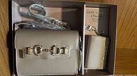 Boxed set showing crossbody bag, strap, and card case wallet