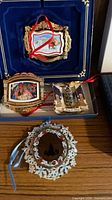 Two boxed White House ornaments and one loose White House ornament displayed on shelf