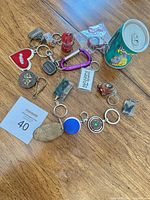 Group of assorted keychains spread on wooden table, showing variety of shapes and materials