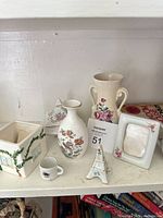 All eight porcelain and ceramic items arranged on shelf