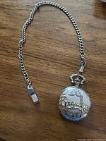 Pocket watch closed with attached chain on wooden surface