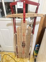 Full view of sled front showing wood slats, red metal frame, Flexible Flyer III handle, printed arrow and eagle graphic