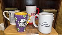Front view of five assorted mugs on shelf