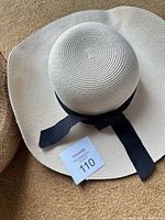 White floppy hat with black ribbon, partial view of other hat