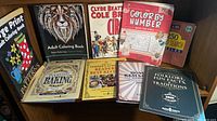 Shelf showing adult coloring, circus, color-by-number and puzzle titles, plus additional paperbacks