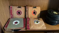 Four cardboard binders filled with 45 RPM records and a loose stack of singles