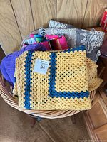 Basket containing four folded lap throws showing colours and patterns