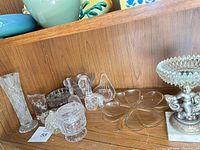 Shelf view showing vase, jar, swans, ashtray, clover plate, compote