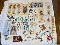 Entire lot laid out showing rosaries, crucifixes, medals and prayer cards