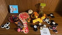 Full lot overview showing spinners, paddles, yo-yo, car, puzzle and timer on shelf