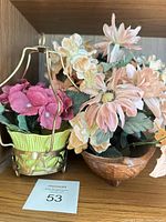 Front view of metal basket planter with magenta hydrangeas and wooden bowl with peach daisies