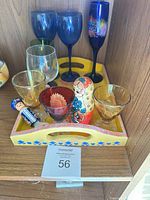 Full lot on shelf showing all glasses, tray, nesting doll, bottle opener