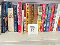 Row of standing books showing dictionary, self-help, sports and fiction titles with lot card 66