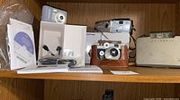 Shelf view showing all five cameras, cases, cables, manual and CD