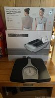 All three boxed and loose items grouped: Sharper Image massager box, LegXercise box, black mechanical scale