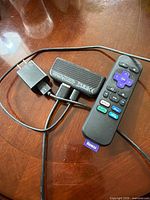 Roku stick, remote, power cable and adapter arranged on table