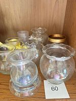Group shot of all five clear iridescent glass votive holders on shelf