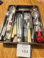 Top view of cutlery tray filled with assorted flatware, bottle and ornament