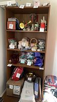 Front view of tall brown bookcase with contents on shelves