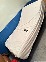 Twin adjustable bed base with raised head section, off-white mattress, remote visible