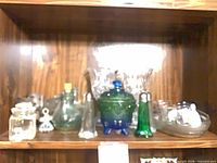 Assorted glassware and tins on shelf, full lot view