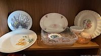 Overall view of shelf showing assorted plates, glass dish, bowls