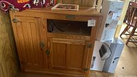 Front view of oak cabinet showing doors, open cubby, hardware, brand plate