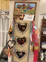 Front view of wooden cubby shelf with heart openings, charms hanging, village scene panel on top