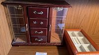 Front view of both jewelry boxes: mahogany cabinet closed and cherry glass-top box