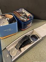 All five watches with respective tins and case visible