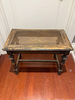 Full view of vanity bench showing caned seat, legs, finish