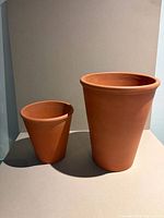 Two terracotta pots side by side, showing height difference