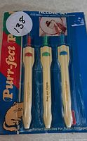 Front view of sealed punch needle set showing three handles with colored caps