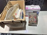 Crate with keyboard, manuals, LG DVD writer box and clear case of discs on table
