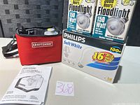 Craftsman laser level in red case, owner’s manual, Philips Soft White bulb pack, two Philips floodlight bulb boxes