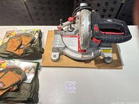 Top view of Craftsman miter saw on wood base with two packaged SideCar tool holders and pouches