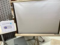 Tripod projection screen next to boxed mini projector