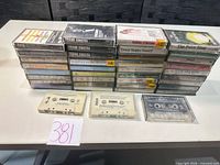 Stack of cassettes in cases plus three loose tapes showing quantity and variety