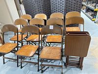 Group view of eleven folding chairs and four stacked tray tables