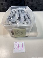 Plastic tub containing individually wrapped stainless steel spoons, sticky note showing 68 total