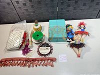 Entire lot laid out showing ribbons, trim, tassel fringe, dolls, fabric scraps, tin