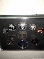 Obverse sides of six coins and medallion in capsule inside case