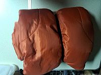 Two rolled rust/burnt orange sleeping bags side by side